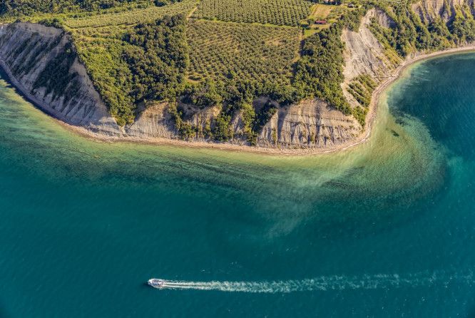 A bird's eye view of a boat dashing along the water of the beach.