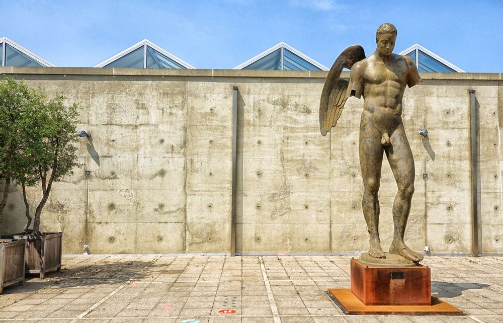 An angel statue with broken arms stands on its own in the sculpture garden at Beelden aan Zee.