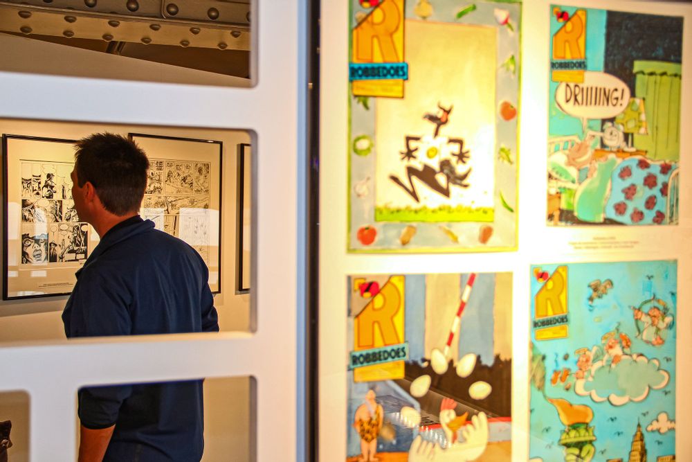 Images of comics on the wall of the Comics Art Museum in Brussels, a visitor is looking at one of them
