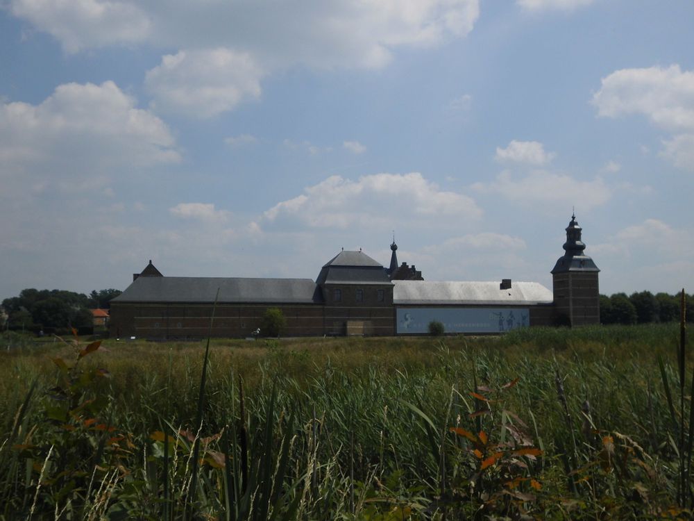 The vast Herkenrode Abbey complex near Hasselt in Belgium sits in the distance behind a grassy field. 