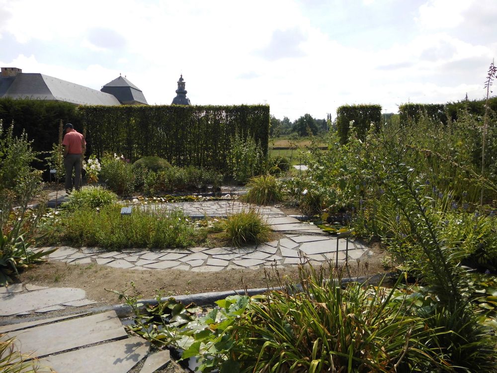 The paved herb garden at Herkenrode Abbey in Hasselt, Belgium is surrounded by tall, trimmed bushes.