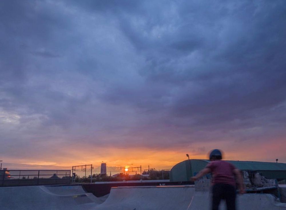 Skateboarder in front of halfpipes at sunset