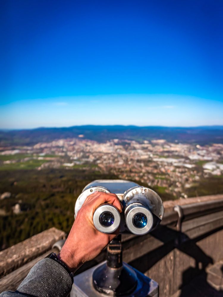 Man holding binoculars overlooking Liberec at Jested, Czechia
