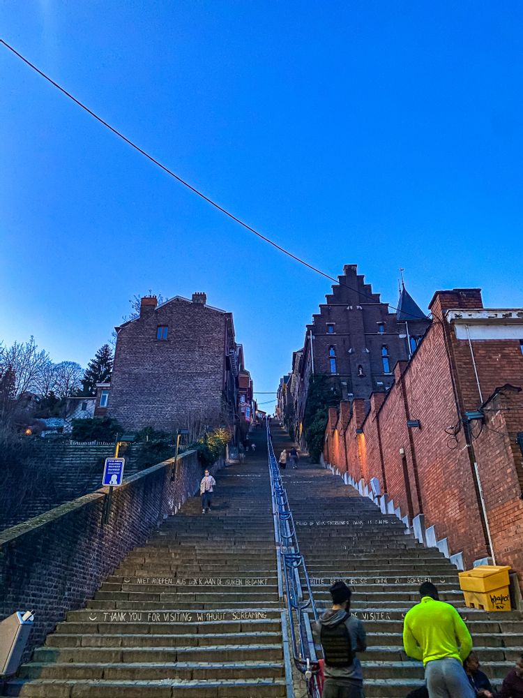 Friend group sitting on the steps at the bottom of Montagne de Bueren, Liege, Belgium