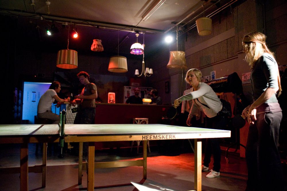 Two girls stand around a ping pong table in one of OT301's bars 