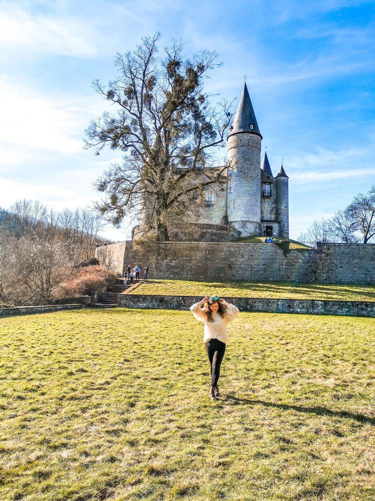 Woman walking in the grass away from the medieval castle Veves Castle, Namur, Belgium