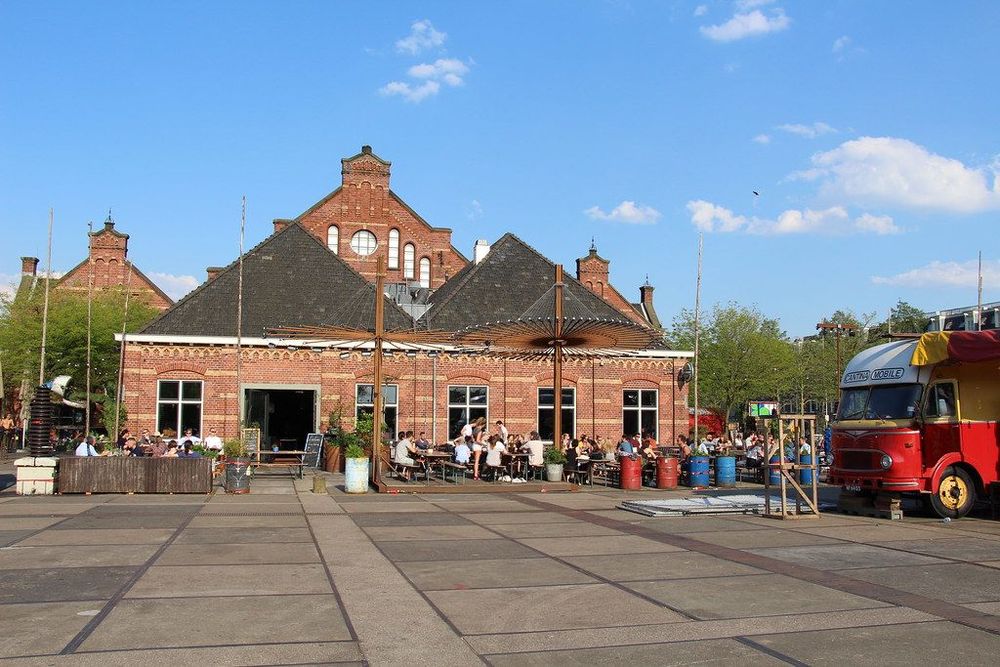 A view of the Westergasfabriek and its terrace with people enjoying the sun.