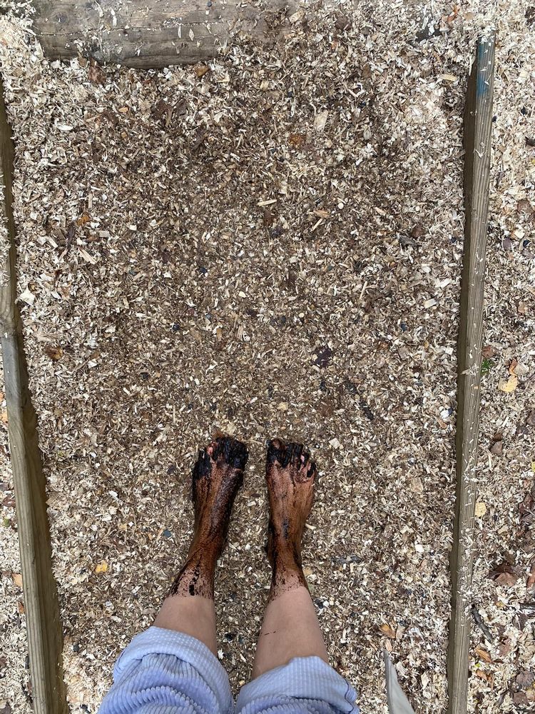 Two muddy bare feet standing in a gravel-like walking path trail along the barefoot path in De Schorre park, Antwerp