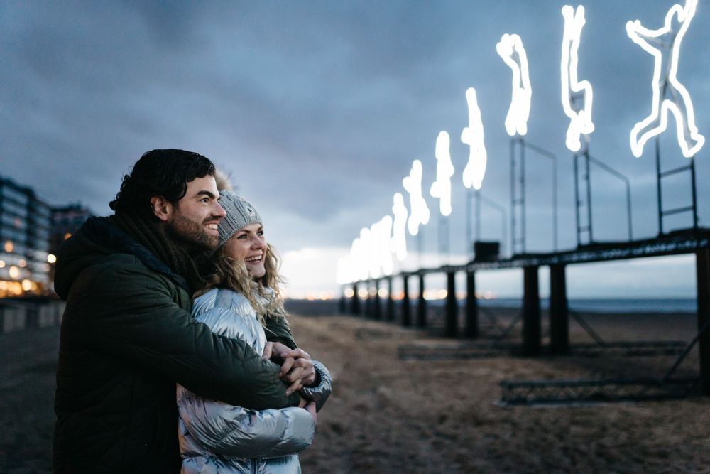 Couple viewing a light art display of a figure running across the beach at the Light ART festival, Knokke-Heist, Belgium