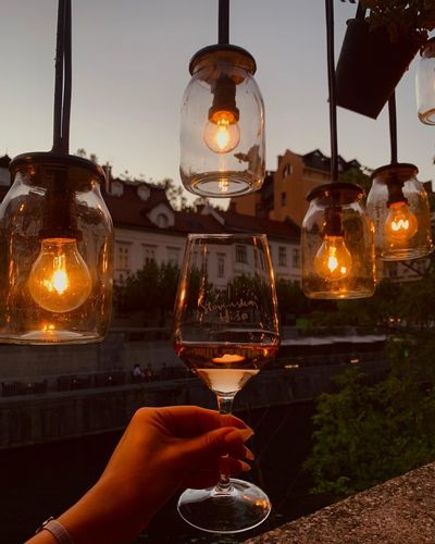 The fairy lights along the waterways at Slovenska Hiša with a hand holding a glass of wine.