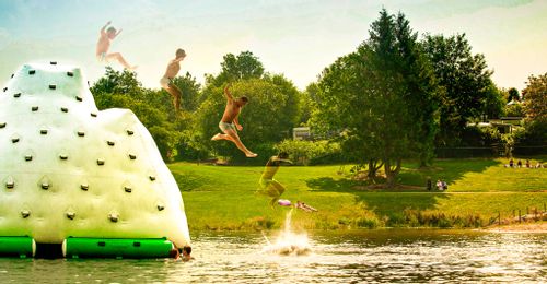 People jumping off the giant inflatable at VENNtastic beach, Lake Butgenbach.